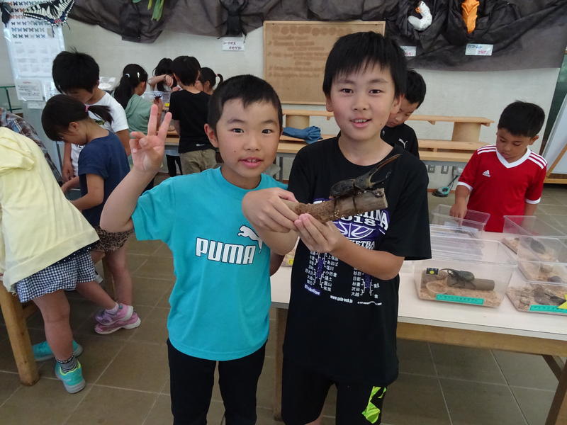 昆虫を手に、にっこり